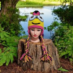 a mannequin head wearing a knitted hat and sitting on a tree stump