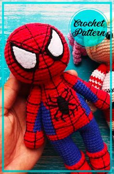 a hand holding a crochet spiderman doll in front of two other stuffed animals