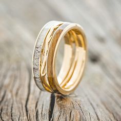 two wedding rings with gold and white wood inlays on a piece of wood