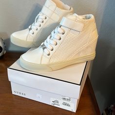 White Faux Leather With Silver Guess Plate In Front. White Synthetic Wedge Sneakers With Round Toe, White Wedge Heel Sneakers For Spring, Trendy White Leather Wedge Sneakers, Trendy White Wedge Sneakers, Spring White Wedge Heel Sneakers, Spring Wedge Sneakers With Perforated Toe Box, White Leather Round Toe Wedge Sneakers, Spring Synthetic Wedge Sneakers With Round Toe, Trendy High-top Synthetic Wedge Sneakers