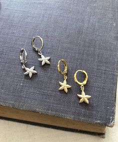 Gold-plated or rhodium-plated huggie hoop earrings measuring 1.2 cm x 1.4 cm with a double sided starfish charm measuring 1 cm. Comes in a black velvet pouch. If these are a gift and you would like a box free of charge please mark the order as gift or leave a message at check out. Nickel-free Star-shaped Huggie Earrings, Silver Drop Earrings With Starfish Charm, Metal Starfish Charm Jewelry, Starfish Charm Hoop Earrings As Gift, Silver Star Charm Huggie Earrings, Starfish Hoop Earrings As Gift, Silver Star Shaped Huggie Earrings With Charm, Jewelry Accessories Ideas, Velvet Pouch