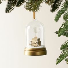 an ornament hanging from a christmas tree with presents under the glass dome on it