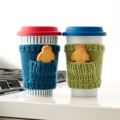 two knitted coffee cups sitting next to each other on top of a computer keyboard