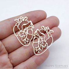 a pair of heart shaped brooches in the palm of someone's hand