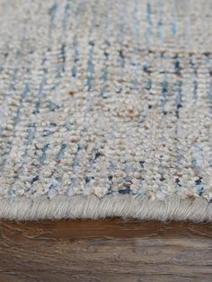 a close up view of a rug on a wooden floor with white and blue colors