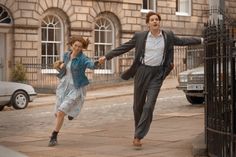 a man and woman are running down the street in front of a gated building