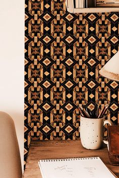 a desk with a pen and notebook on it next to a wallpapered wall