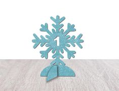 a paper snowflake on a wooden table with white wall in the back ground