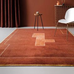 a chair and table in a room with an orange rug on the floor next to a window