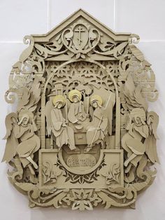 an intricately carved wooden plaque depicting the birth of jesus on a white wall in a church