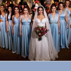 a group of women standing next to each other wearing blue bridesmaid gowns