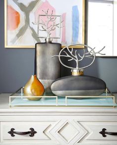 two vases are sitting on top of a white dresser in front of a painting