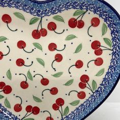 a heart shaped dish with cherries painted on it