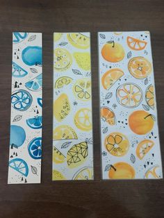 three pieces of paper with oranges and lemons painted on them sitting on a table