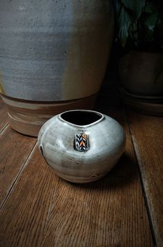 This round jar is perfect for flower arranging or an accent to your decor! I made this jar on the potter's wheel from recycled multicolored clay. The upper portion is glazed with a semi transparent, glossy white glaze. The lower portion is unglazed, so the distinct colors of the clay are visible. My handprints left from the glazing process are visible on both sides. The clay is reclaimed and is several shades of brown, cream and black. This jar is five inches tall and six and one half inches in diameter. It weighs two pounds seven ounces. This piece has a unique colored clay accent insert on the upper portion. The accent is orange, black and white in a marbled or feathered pattern. The insert was added while the clay was wet and created an indent in the clay. The moon jar is the epitome of Ikebana Vases Pottery, Ikebana Arrangement, Vases Pottery, Moon Jar, Ikebana Flower, Ikebana Arrangements, Arrangement Floral, Ikebana Vases, Jar Vase