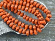 an orange beaded necklace on a metal spoon