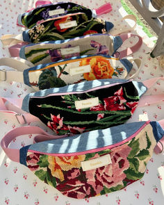 four small purses lined up on top of a table with flowers and ribbons around them