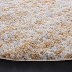 a white and yellow rug on top of a wooden floor next to a black table