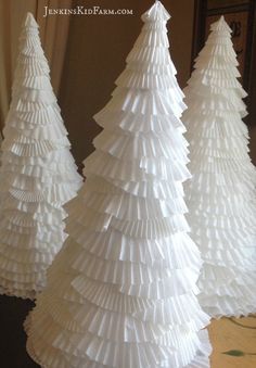 three white paper christmas trees sitting on top of a table