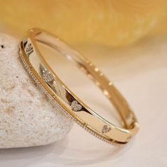 There are so many ways to love this fresh and fun cubic zirconia bangle bracelet. This darling bangle features heart designs made with CZ stones which adorns a band on one side. A meaningful look for the one you adore. - Stones Material: Cubic Zirconia. - Stones Shape: Round. - Metal: Brass. - Plating: 18k Gold plated. - Interior Diameter: 60 mm. - Width: Aprox. 5 mm. - Clasp: Snap Closure. - Circumference Inches: 7.42 Ships in a Balara Gift Pouch. Available in Gold. SKU# B1683 Gold Kada Design For Women Stylish, Gold Band Bracelet For Women, Ladies Bangle Design, Indian Gold Bracelet For Women, Bracelet Bangles For Women, Bangle Gold Designs, Gold Kada Design For Women Indian, Elegant Stackable Heart Bracelet, Cubic Zirconia Bangle Bracelet For Valentine's Day