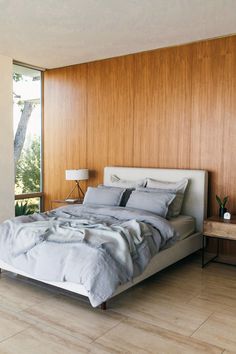 a large bed sitting in the middle of a bedroom next to a wall with wood paneling