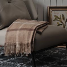 a chair with a blanket on top of it next to pillows and a framed photograph