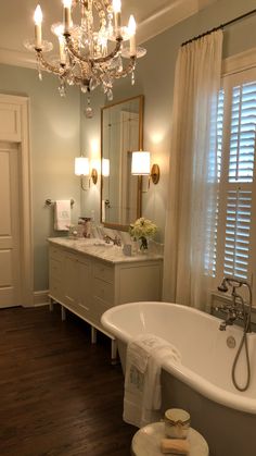 a bathroom with a claw foot tub and chandelier