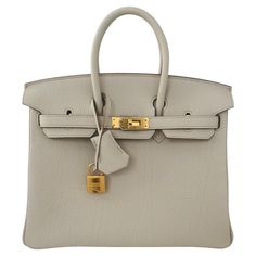 Hermes Birkin 25cm Beton, a classic netral color from Hermes, a creamy Ivory with some grey undertones Gold Hardware The Hermes Birkin is a luxury handbag from the fashion house Hermes. It is a variation of the iconic Hermes Birkin bag, which was first introduced in 1984 and has since become one of the most sought-after luxury handbags in the world. The Beton Birkin is a classic color , one of their prettiest neutrals. It is made from togo leather and features the signature Hermes lock and key closure, as well as the brand's signature Gold hardware. This particular Birkin has the most beautiful shape and togo leather, one of the best we have seen recently. The interior is lined with chevre and has a zip pocket with an Hermes engraved zipper pull and an open pocket on the opposite side. Col Hermes Birkin Bag, Twilly Scarf, Hermes Birkin 25, Fashion Vocabulary, Girly Bags, Hermes Box, Togo Leather, Luxury Purses, Birkin 25