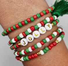 three different bracelets with the word joy written on them and green tasseled beads