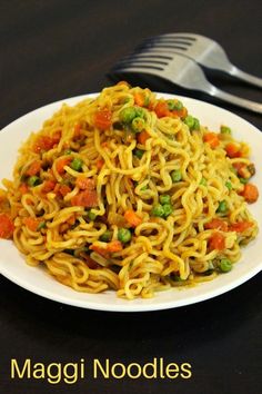 a white plate topped with noodles and vegetables next to a fork on a table top