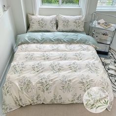 a bed with white and blue comforters in a small room next to a window