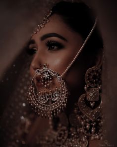 a woman in a bridal outfit with jewelry on her face and headdress