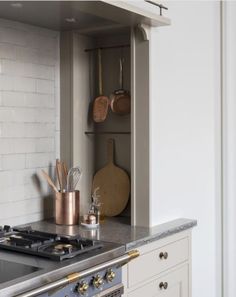 a stove top oven sitting inside of a kitchen next to a wall mounted oven hood