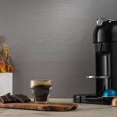 a cup of coffee sitting on top of a counter next to a wooden board with chocolate