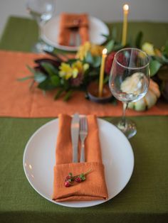 the place setting is set with orange napkins and silverware, along with candles