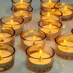 many lit candles in glass bowls on a table