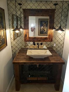 a bathroom sink sitting under a mirror next to two framed pictures