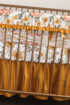 a baby crib with yellow and orange floral bedding