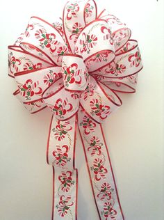 a red and white bow with flowers on it's side, hanging from the wall