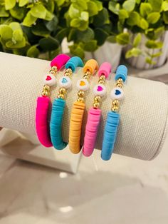 four different colored bracelets on top of a white napkin next to a potted plant