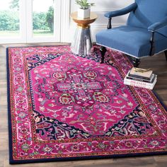 a bright pink rug with an ornate design on the floor in front of a blue chair