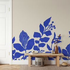 a room with blue flowers painted on the wall and a wooden table in front of it