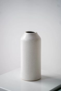 a white vase sitting on top of a table