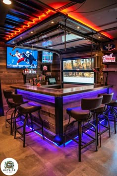 a bar with several stools in front of it and two television screens on the wall