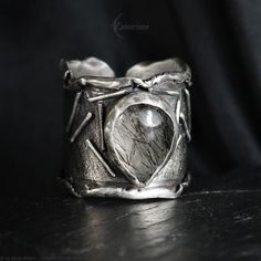 Modern, Brutalist-style Textured Ring. Fully handmade work.  Oxidized 925 Sterling Silver and 999 Fine Silver. The main accent of this ring is a natural Turmaline Quartz. Material: 925 Sterling Silver,999 Fine Silver, Turmaline Quartz. The height of the central part is 2.2 cm. Size: Adjustable. Color: Silver, Black. Artisan Untreated Open Ring Jewelry, Unique Hand Forged Open Moonstone Ring, Unique Hand Forged Moonstone Open Ring, Artisan Moonstone Ring, Artisan Hand Forged Open Ring Jewelry, Artisan Hand-forged Open Ring Jewelry, Unique Silver Moonstone Ring, Artisan Ring With Oxidized Finish, Mystical Hand Forged Silver Rings