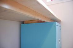 a blue refrigerator sitting on top of a wooden shelf