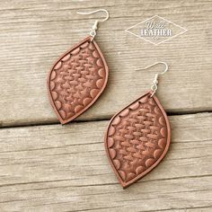 two pairs of leather earrings on top of a wooden table