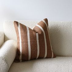 a brown and white striped pillow sitting on top of a couch next to a wall