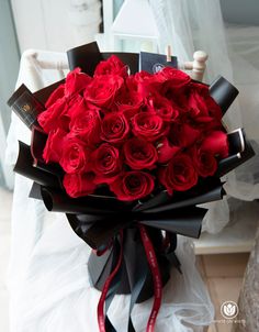 a bouquet of red roses wrapped in black paper