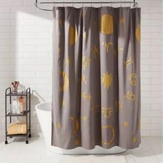 a shower curtain with yellow and gray designs on it in a white tiled bathroom next to a bathtub